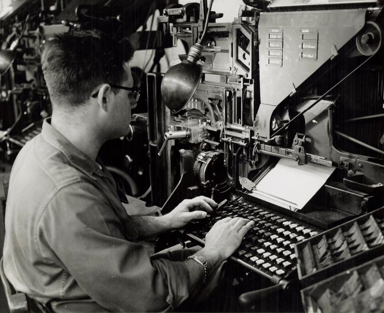 young man in glasses types at machine