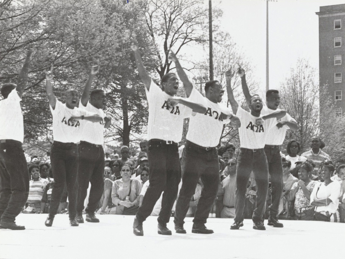 memebrs of a black fraternity fance on a stage in front of a crowd