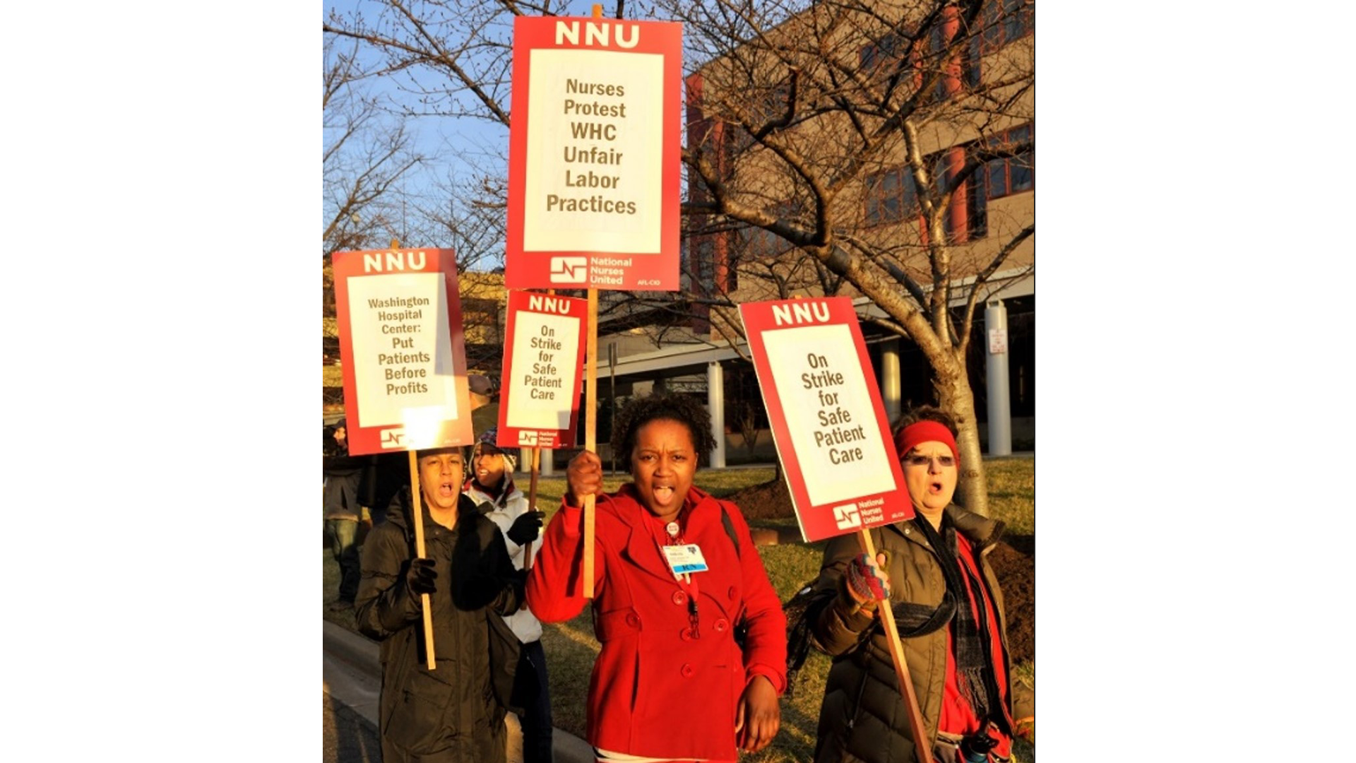A group of nurses hold picket signs