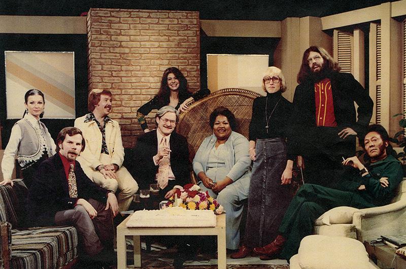 a group of eight people pose in a living room