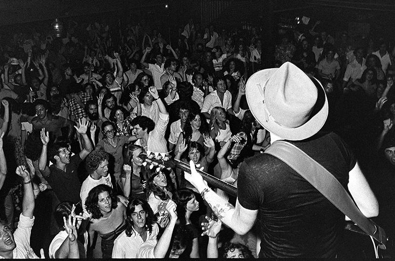 Crowd cheering while the Nighthawks perform, photo shows the back of a guitar player